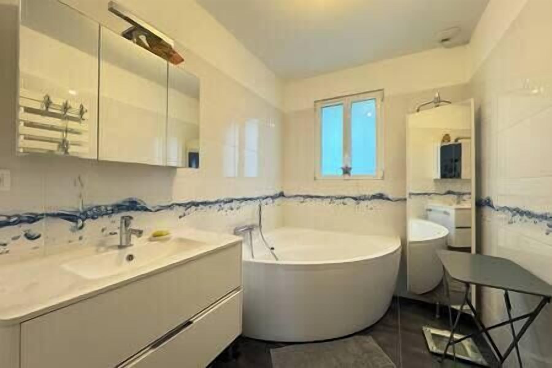 Un baño moderno con bañera, lavamanos y espejo.