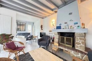 A living room with a fireplace, seating area, and a television. - Les Sylphes - Parking, WiFi, TV, 350m to the beach (Pornichet)