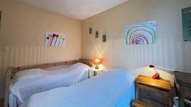 Ein Zimmer mit zwei Betten, einem Nachttisch mit Lampe sowie Wandbildern.