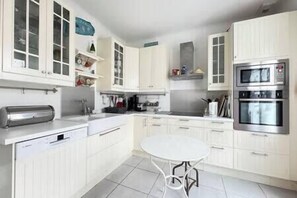 A modern kitchen with white cabinetry, a built-in oven, and a stainless steel dishwasher. - Les Sylphes - Parking, WiFi, TV, 350m to the beach (Pornichet)