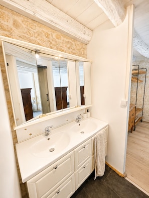 A bathroom with a double sink, a large mirror, and a wooden floor.