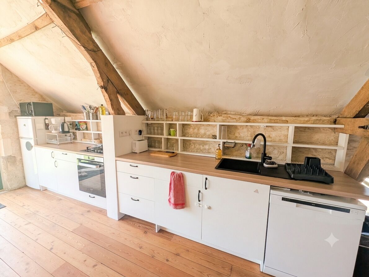 Une cuisine avec des armoires blanches, un plan de travail en bois, un évier et un dosseret carrelé.