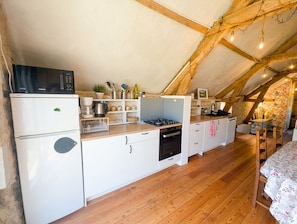 A compact kitchen with a microwave, stove, and refrigerator.