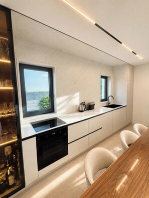 A modern kitchen with a built-in dishwasher, a window with a view, and a bar area with glasses. - Luxury Villa MariQ  Heated Pool  Near Rovinj (Žminj)