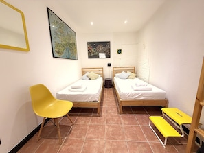 A small, clean room with two single beds, a yellow chair, and a bench. - Principino - Walk to the Old Port and the Aquarium; take the train to the Cinque Terre. (Genova)