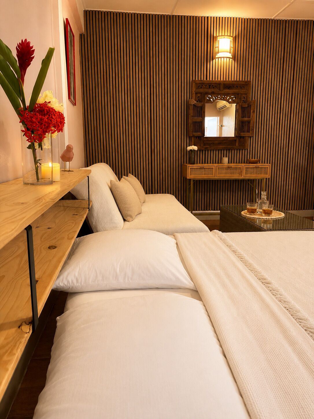 A hotel room with a bed, bedside table, and a mirror.