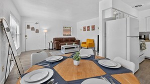 A modern kitchen with white cabinets, a white refrigerator, and a microwave.