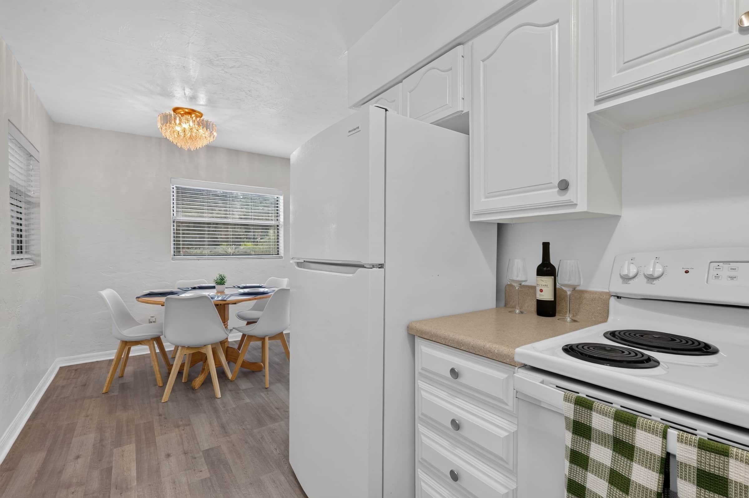Ett modernt kök med vita skåp, en matplats med bord och stolar samt en inbyggd ugn.