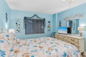 A bedroom with a bed, dresser, television, and decorative wall art. - Top Floor Gulf Front • Pool • Sand Castle North 503 (Indian Rocks Beach)