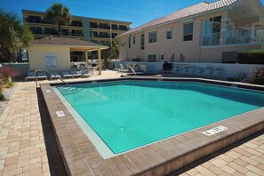 Une piscine dotée d’une terrasse carrelée, de chaises longues et d’un panneau indiquant les règles d’utilisation de la piscine.