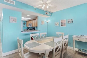 A dining area with a round table, four chairs, and a ceiling fan. - Top Floor Gulf Front • Pool • Sand Castle North 503 (Indian Rocks Beach)