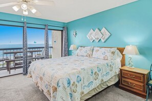 Ein Schlafzimmer mit einem Bett, einem Nachttisch, einer Lampe und Blick aufs Meer.
