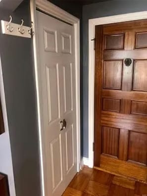 A closed white door with a silver handle and a wooden door with a brass doorknob.