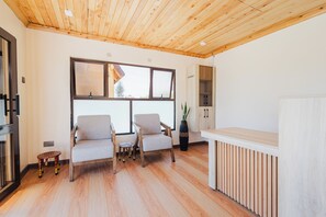 Ein modernes Interieur mit Holzboden, zwei Sesseln, einem kleinen Tisch, einem Schrank und einer Heizung.