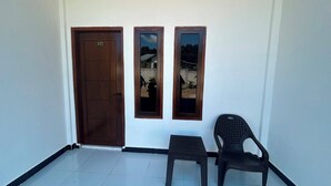 A room with a wooden door marked '02', a small stool, and a plastic chair. - Wae Tuak Home Stay (Labuan Bajo)