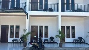 A multi-story building with balconies, potted plants, and a parked motorcycle. - Wae Tuak Home Stay (Labuan Bajo)