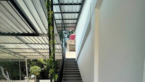 A staircase leading to an upper level with a metal roof and a wooden reception desk at the bottom. - Wae Tuak Home Stay (Labuan Bajo)