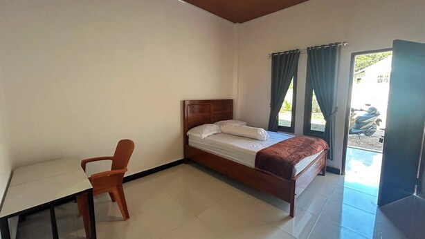 A bedroom with a bed, a desk, and a chair. - Wae Tuak Home Stay (Labuan Bajo)