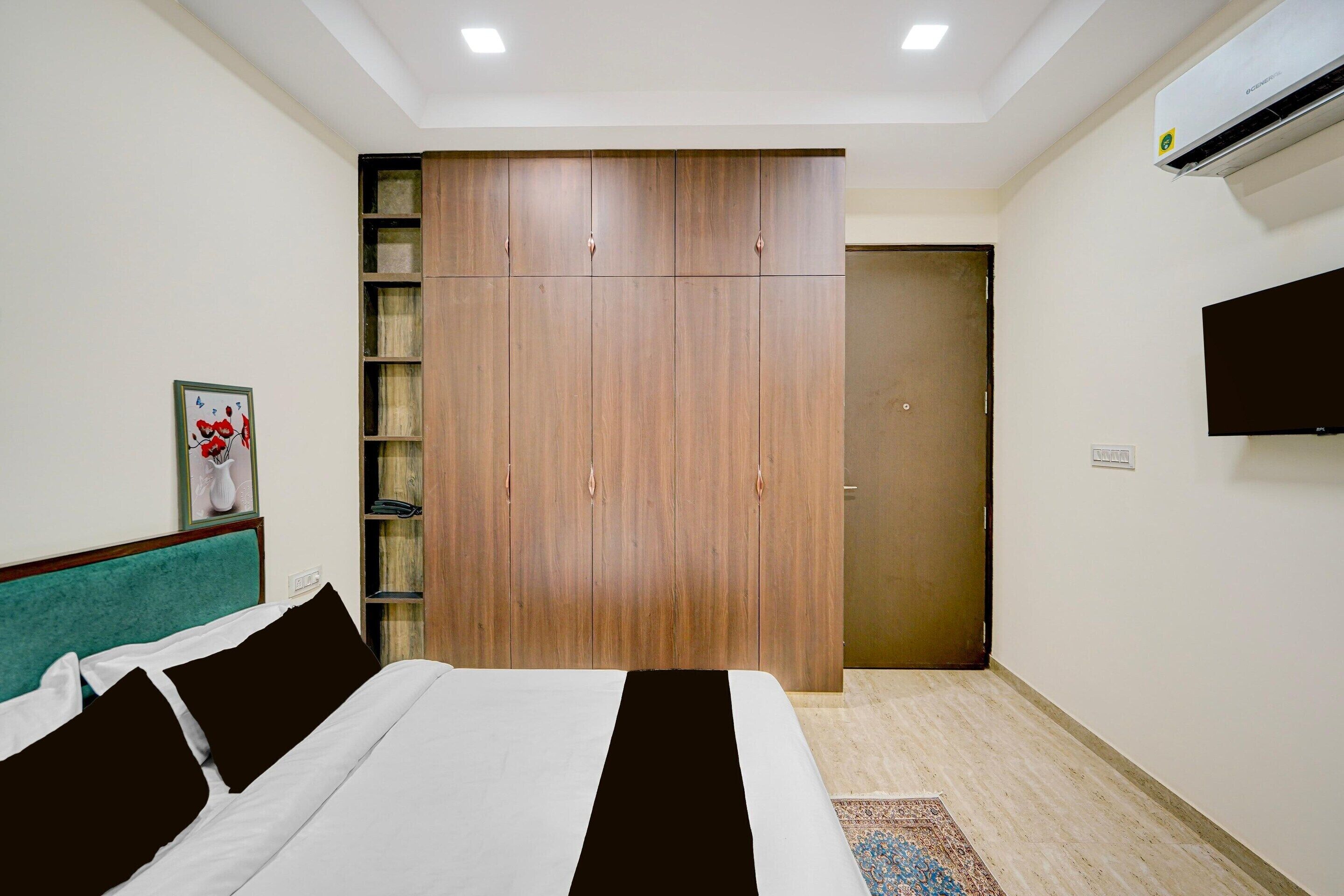 A hotel room with a bed, a wardrobe, a television, and a door.