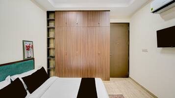 A hotel room with a bed, a wardrobe, a television, and a door.