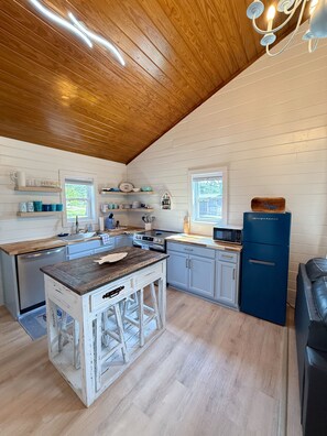 Cocina con techo de madera, paredes blancas y una isla central.