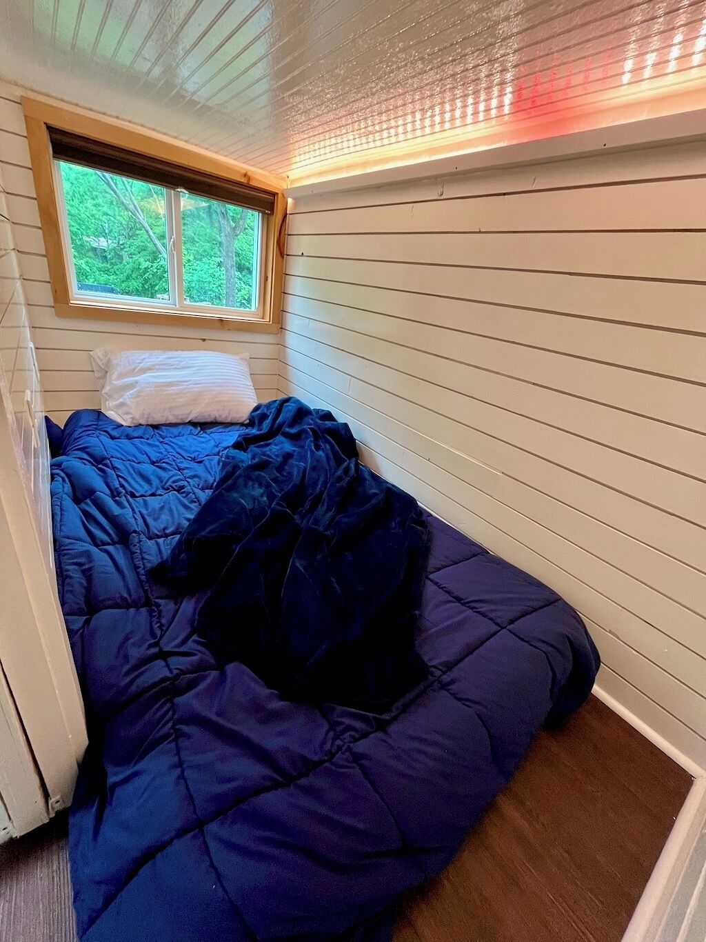 A bedroom with a bed, a window, and a ceiling with a light fixture.