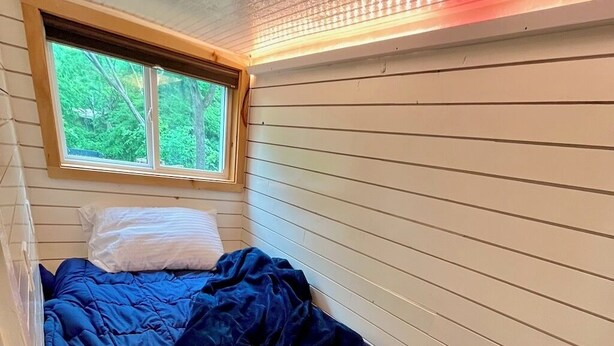 Et soveværelse med en seng, et vindue og en loftlampe.
