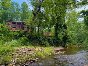 Eine Hütte mit einer Holzterrasse und einem Fluss im Hintergrund.