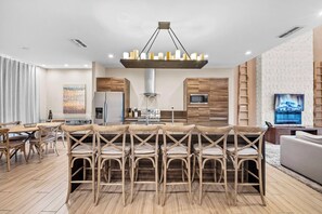 Een moderne keuken met een centraal eiland, roestvrijstalen apparatuur en een hangende lamp.