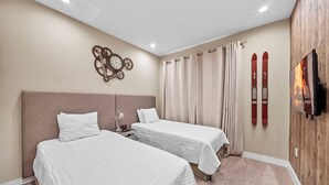 Ein Hotelzimmer mit zwei Betten, einer Uhr, Vorhängen und Ski, die an der Wand befestigt sind.