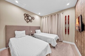 A hotel room with two beds, a clock, curtains, and skis mounted on the wall. - 4BR house sleeps 10 in Magic Village Views (Kissimmee)