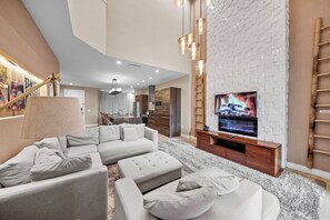 A modern living room with a sofa set, a TV, and a fireplace. - 4BR house sleeps 10 in Magic Village Views (Kissimmee)