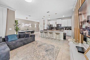 A modern living room with a grey sofa, a coffee table, and a TV on a stand. - 4BR house sleeps 8 with private pool (Kissimmee)