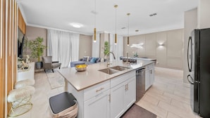A modern kitchen with a central island, white cabinetry, and pendant lighting. - 4BR house sleeps 8 with private pool (Kissimmee)