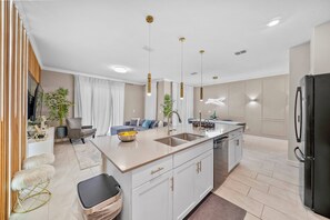 A modern kitchen with a central island, white cabinetry, and pendant lighting. - 4BR house sleeps 8 with private pool (Kissimmee)