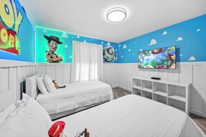 A bedroom with two beds, a TV, and a wall with a blue sky design. - 4BR house sleeps 8 with private pool (Kissimmee)