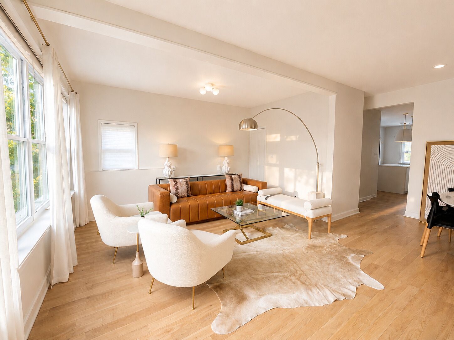 A modern living room with a sofa, armchairs, a glass coffee table, and a leather rug.