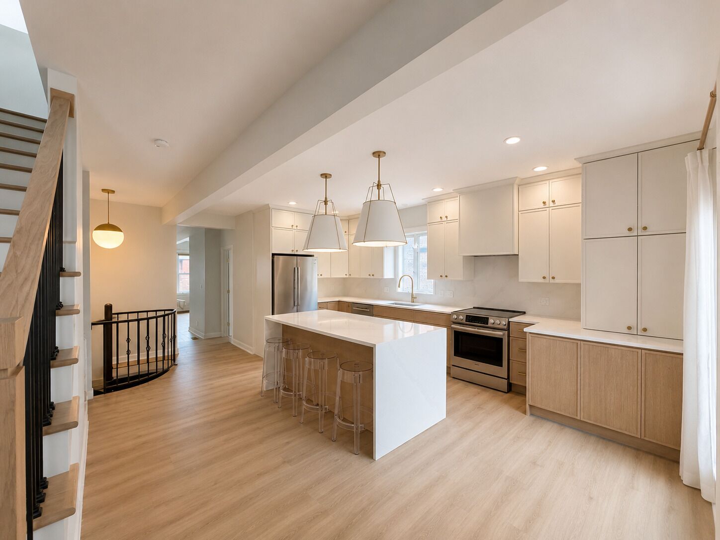 A modern kitchen with a central island, stainless steel appliances, and light wood cabinetry.