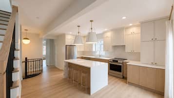 A modern kitchen with a central island, stainless steel appliances, and light wood cabinetry.