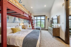 Ein Hotelzimmer mit einem Etagenbett, einem Schreibtisch, einem Fernseher und einem großen Fenster.