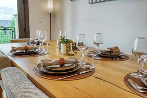Ein Esstisch mit Geschirr, Besteck und Weingläsern, mit einer Pflanzenarragement in der Mitte.