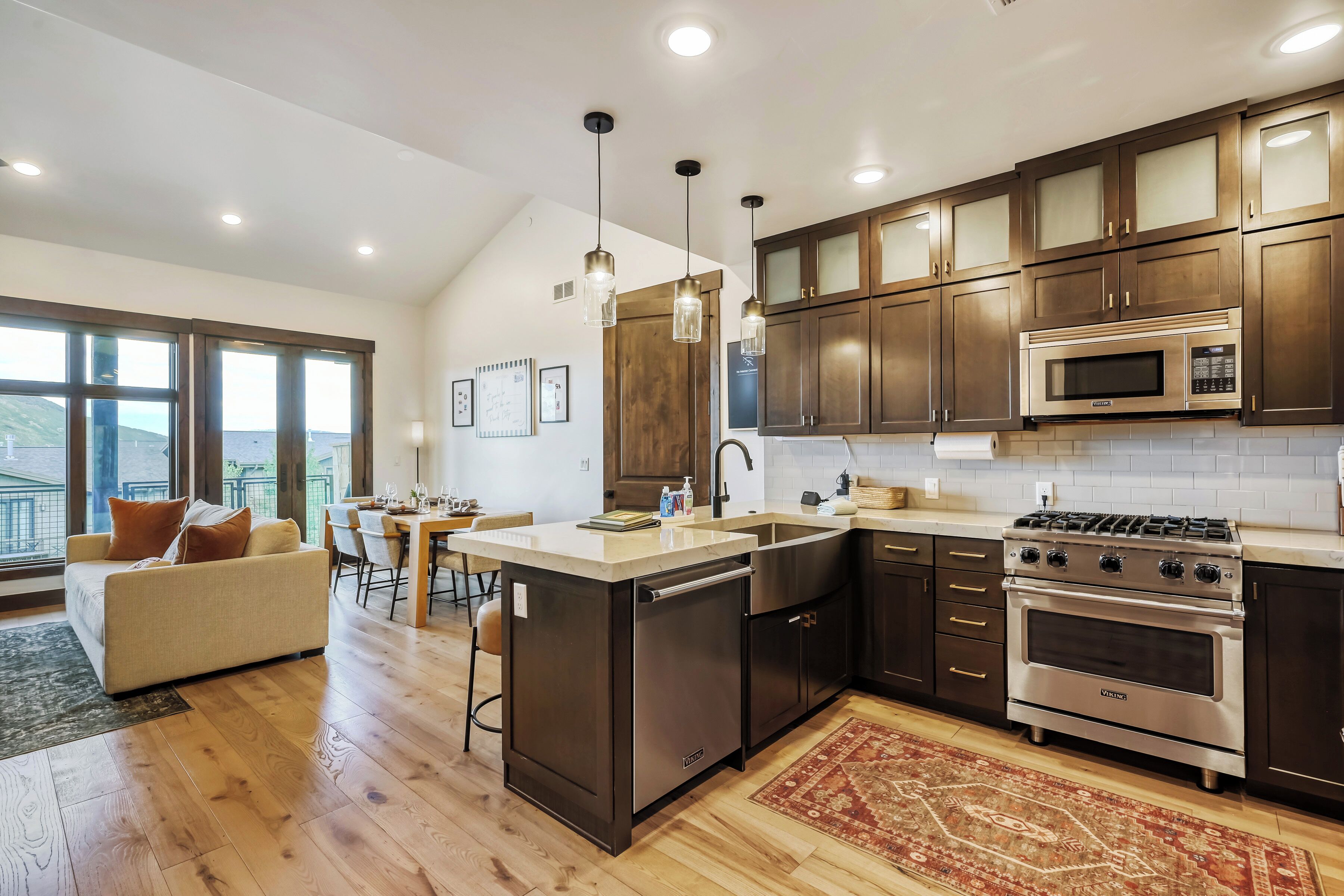 A modern kitchen with dark wooden cabinets, stainless steel appliances, and a large island.