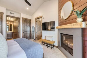 Ein Schlafzimmer mit einem Bett, einer Bank, einem Kamin und einem Spiegel.
