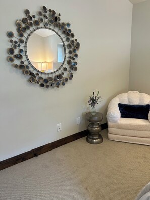 A living room with a round mirror, a small side table with a vase, and a plush sofa. - 1491 April Mountain Drive (Park City)