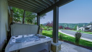 A hot tub under a covered patio with a view of a residential street and hills. - 1491 April Mountain Drive (Park City)