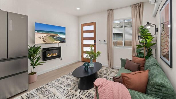A modern living room with a flat-screen TV, a fireplace, a sofa, and a dining table. - Walk to Beach (3 Blks)! 2BR/2-Beds PB Gem + AC - Holiday Home (San Diego)