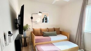 A compact bedroom with a bed, a ceiling fan, a wall-mounted TV, and a small bedside table with a lamp. - Walk to Beach (3 Blks)! 2BR/2-Beds PB Gem + AC - Holiday Home (San Diego)