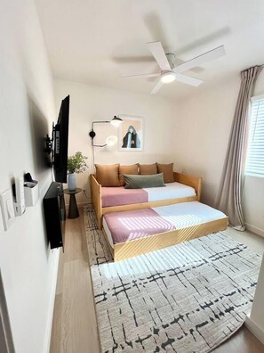 A compact bedroom with a bed, a ceiling fan, a wall-mounted TV, and a small bedside table with a lamp. - Walk to Beach (3 Blks)! 2BR/2-Beds PB Gem + AC - Holiday Home (San Diego)