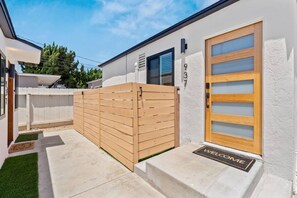 A modern house with a wooden gate, a white exterior, and a welcome mat. - Walk to Beach (3 Blks)! 2BR/2-Beds PB Gem + AC - Holiday Home (San Diego)