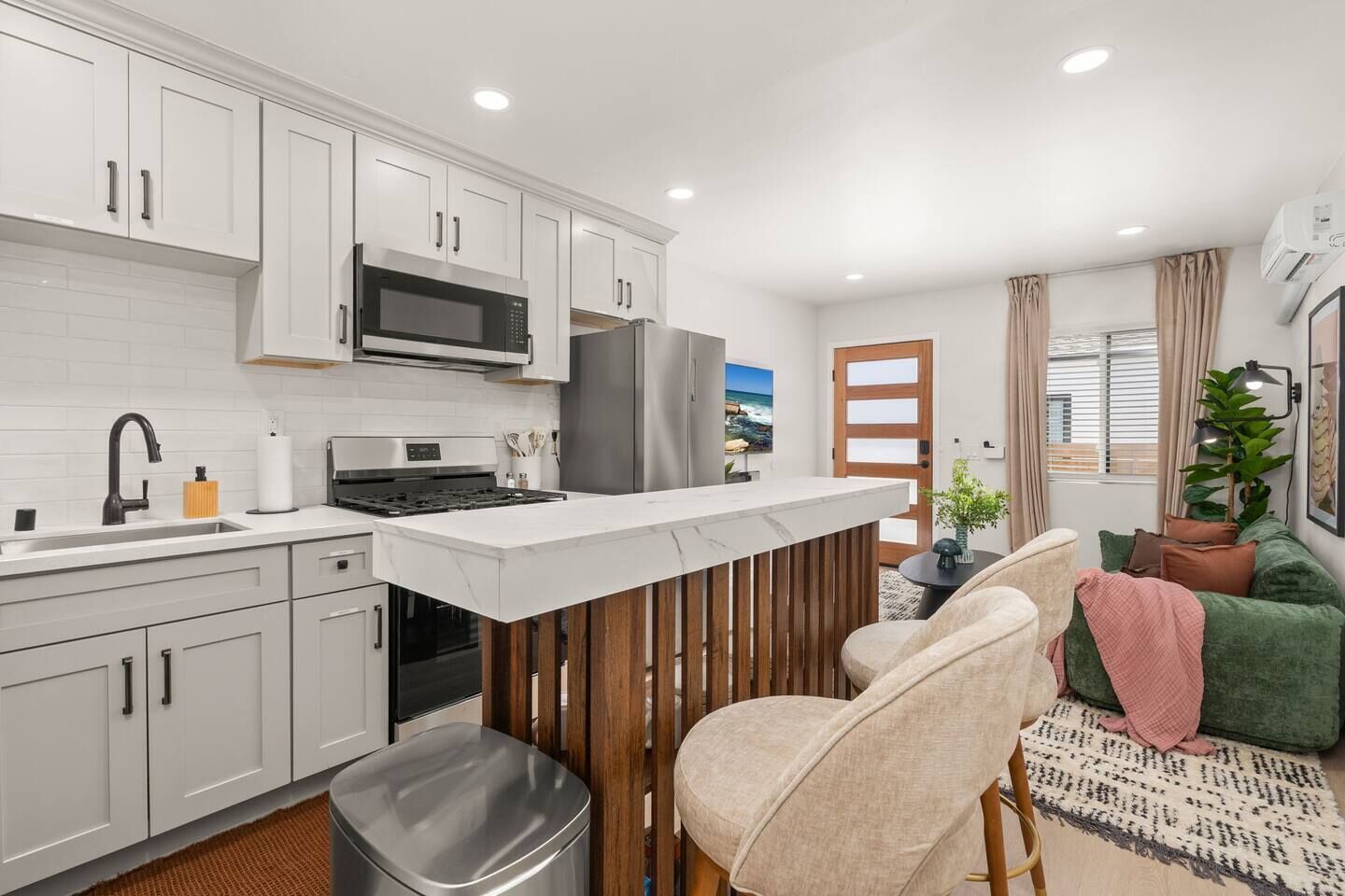 A modern kitchen with white cabinets, a stainless steel refrigerator, and a wooden island.